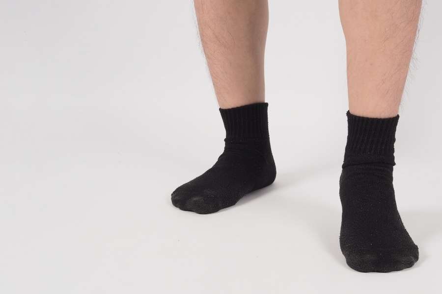 Gros plan sur des pieds portant des chaussettes coton peigné noires sur fond blanc.