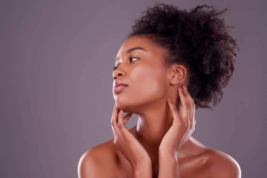 Profil d'une femme noire affichant un teint zéro défaut lumineux et une peau parfaitement unifiée.