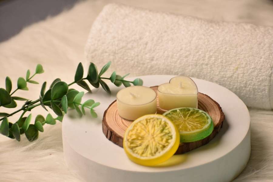 Décoration zen avec des bougies, des rondelles de citron et des branches d'eucalyptus pour préparer une journée spa parfaite.