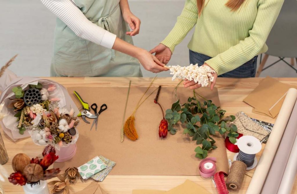 Deux femmes sélectionnent des fleurs séchées et de l'eucalyptus pour un tuto deco mariage diy facile a faire soi meme.